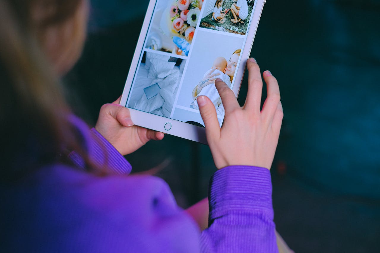 Crop anonymous female looking at screen of tablet with photos while sitting in room